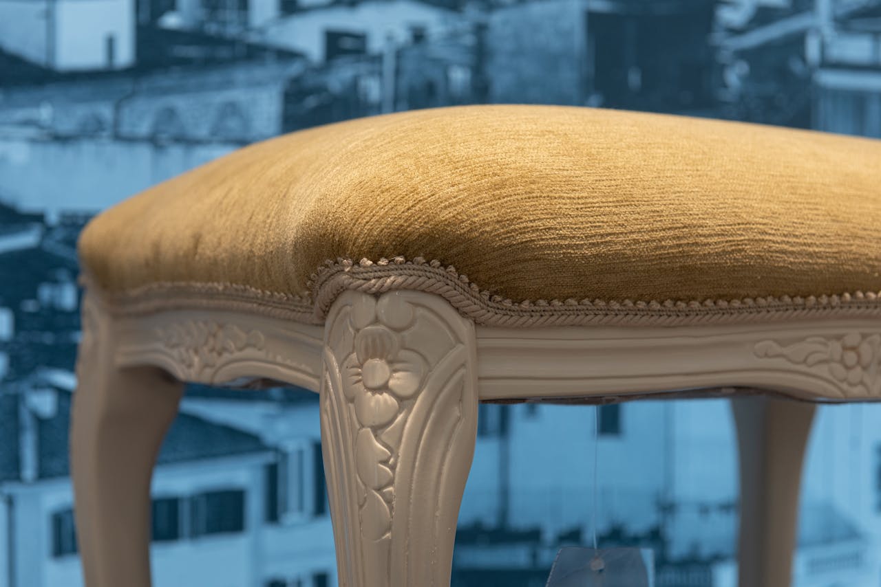 Vintage white wooden stool with details and soft seat in apartment with picture of city on wall